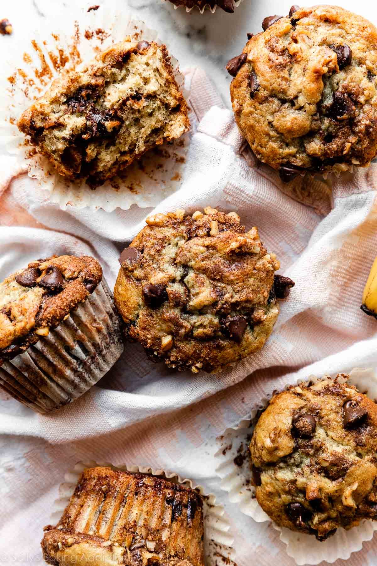 6 banana chocolate chip cinnamon streusel muffins on pink and white linen.