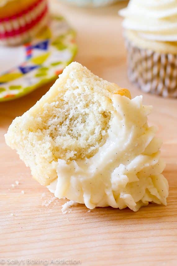 vanilla cupcake topped with vanilla buttercream with a bite taken from it