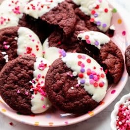 red velvet cookies dipped in white chocolate with Valentine's Day heart sprinkles on top