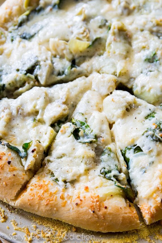 sliced spinach artichoke pizza on a pizza pan