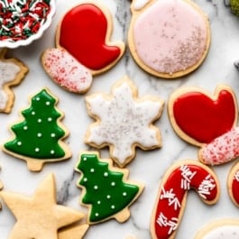 decorated Christmas sugar cookies including Christmas tree, red mittens, ornaments, and snowflakes with icing.