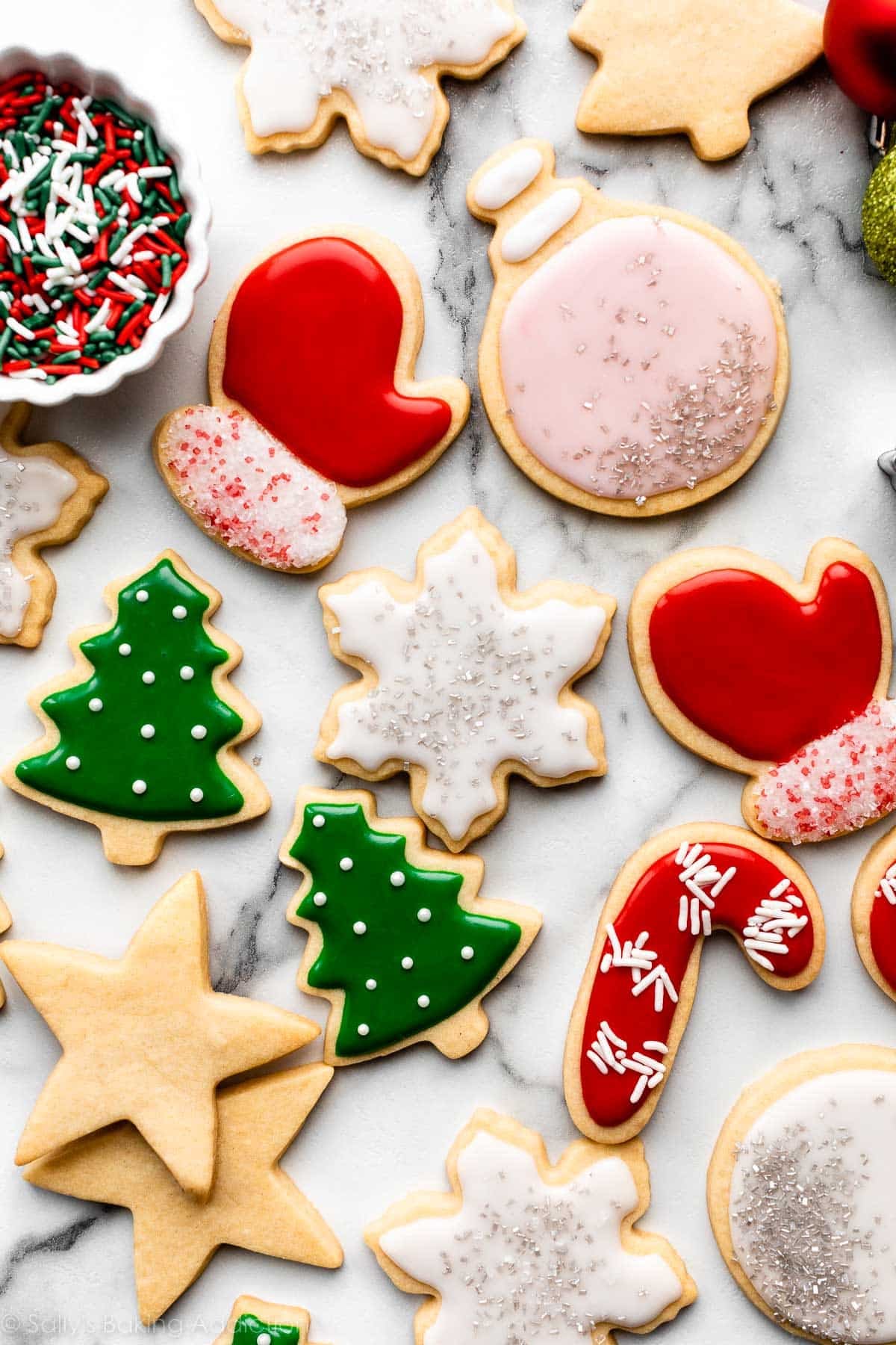 decorated Christmas sugar cookies including Christmas tree, red mittens, ornaments, and snowflakes with icing.