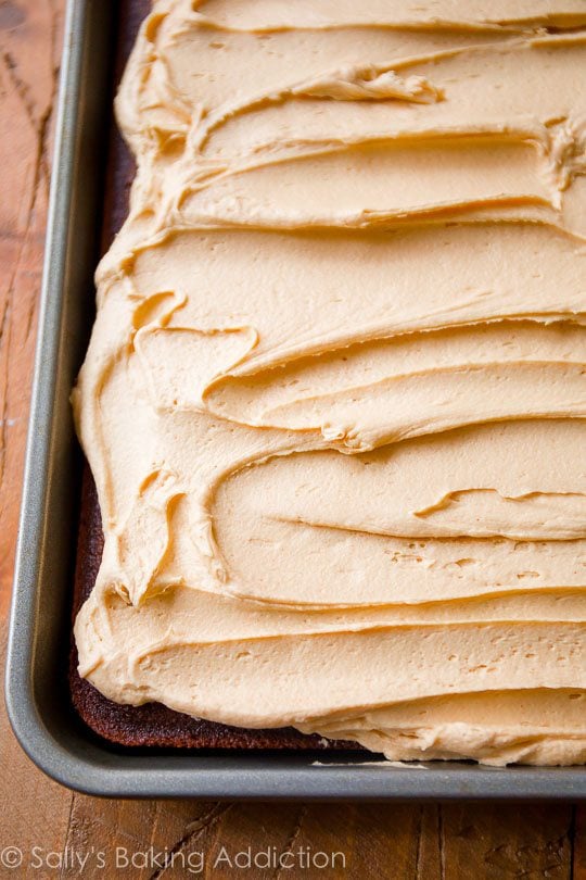 spreading peanut butter frosting onto chocolate sheet cake