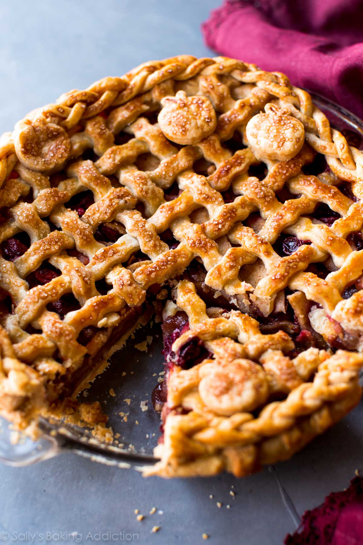 apple cranberry pie in a glass pie dish with a slice cut