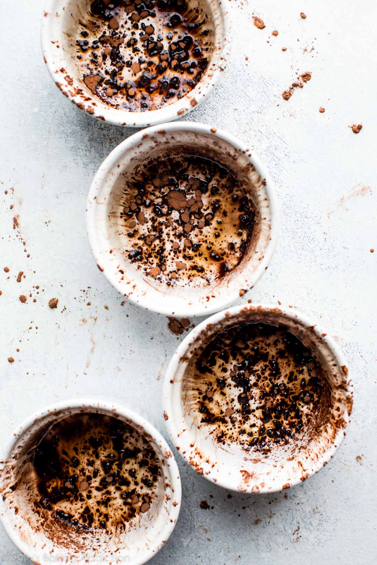 overhead image of white ramekins with a dusting of cocoa powder inside