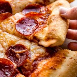 hands pulling out a slice of stuffed crust pizza