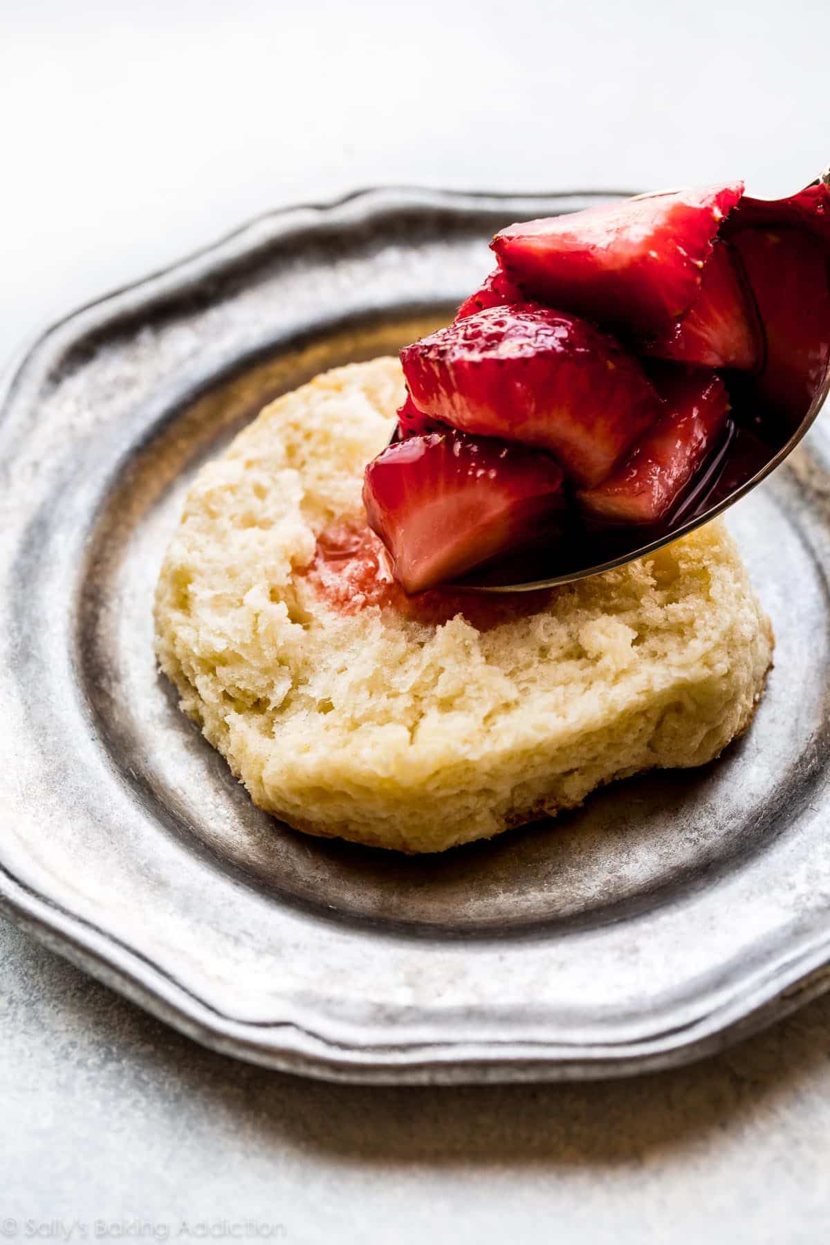 spooning strawberries onto biscuit and assembling strawberry shortcake