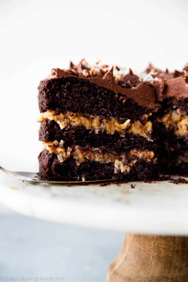 slice of German chocolate cake on a cake server on a marble cake stand