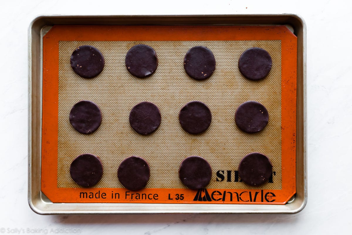 Circle shaped chocolate sugar cookie dough on silpat lined baking sheet before baking