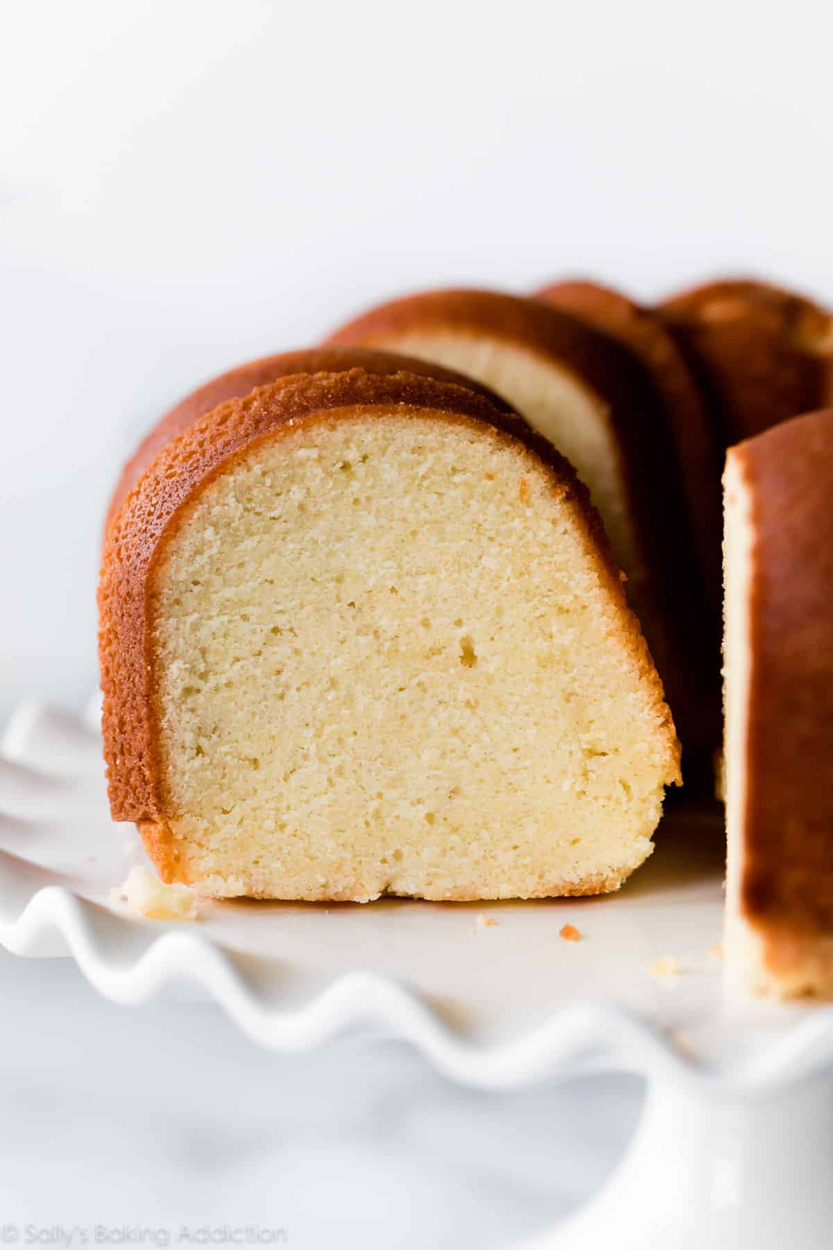 Cream cheese pound cake on a white ruffled cake stand