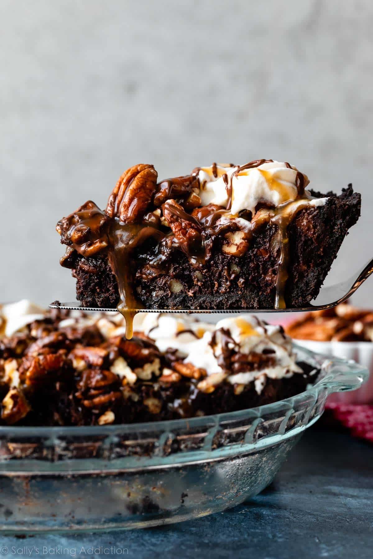 slice of caramel pecan brownie pie being removed from pie dish.
