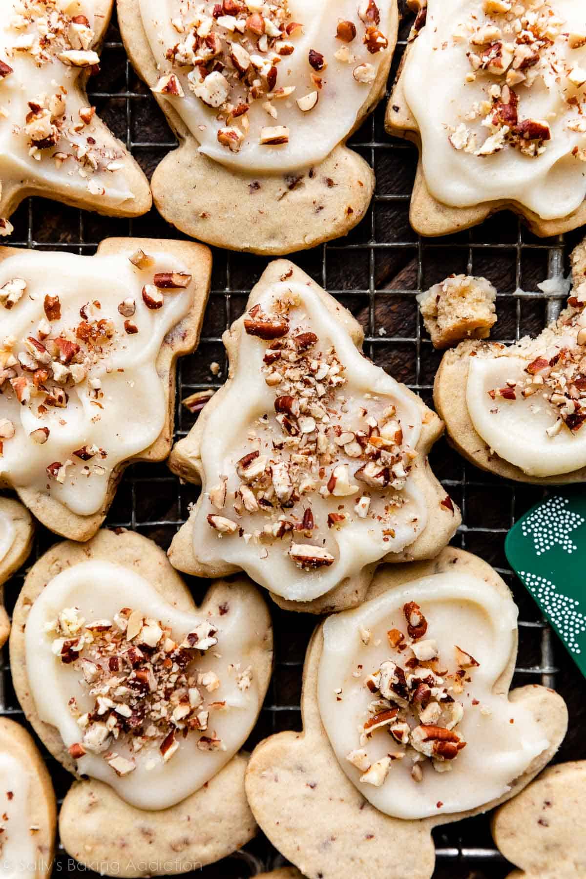 pecan sugar cookies with icing and crushed pecans on top in the shape of mittens and Christmas tree.
