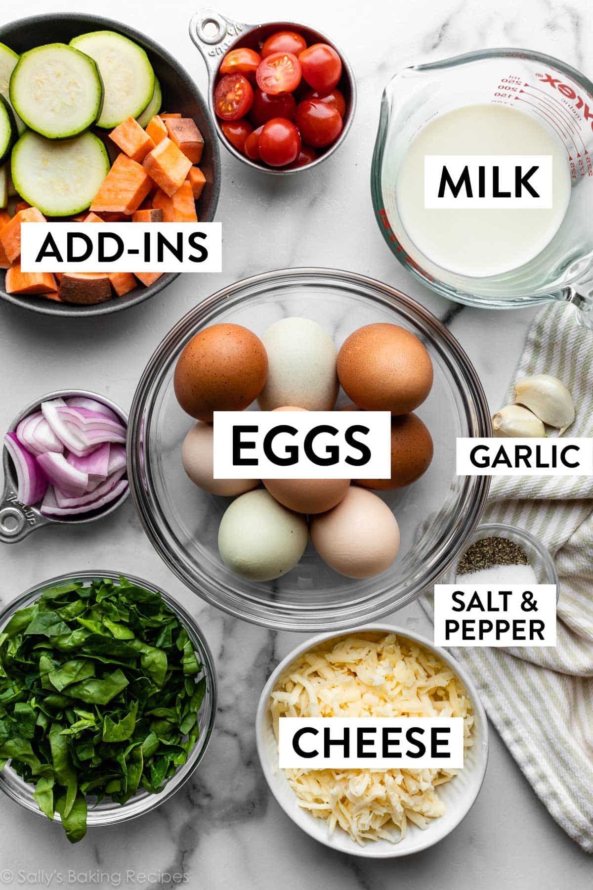 ingredients in bowls including milk, eggs, cheese, salt and pepper, chopped spinach, cherry tomatoes, and more.