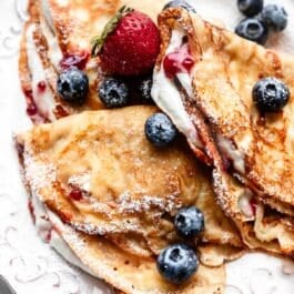 homemade crepes with whipped cream, berries, and raspberry jam.