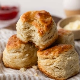3 homemade biscuits in a pile on striped linen.