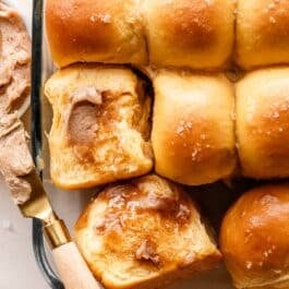 sweet potato rolls with cinnamon butter and sea salt on top in glass dish.