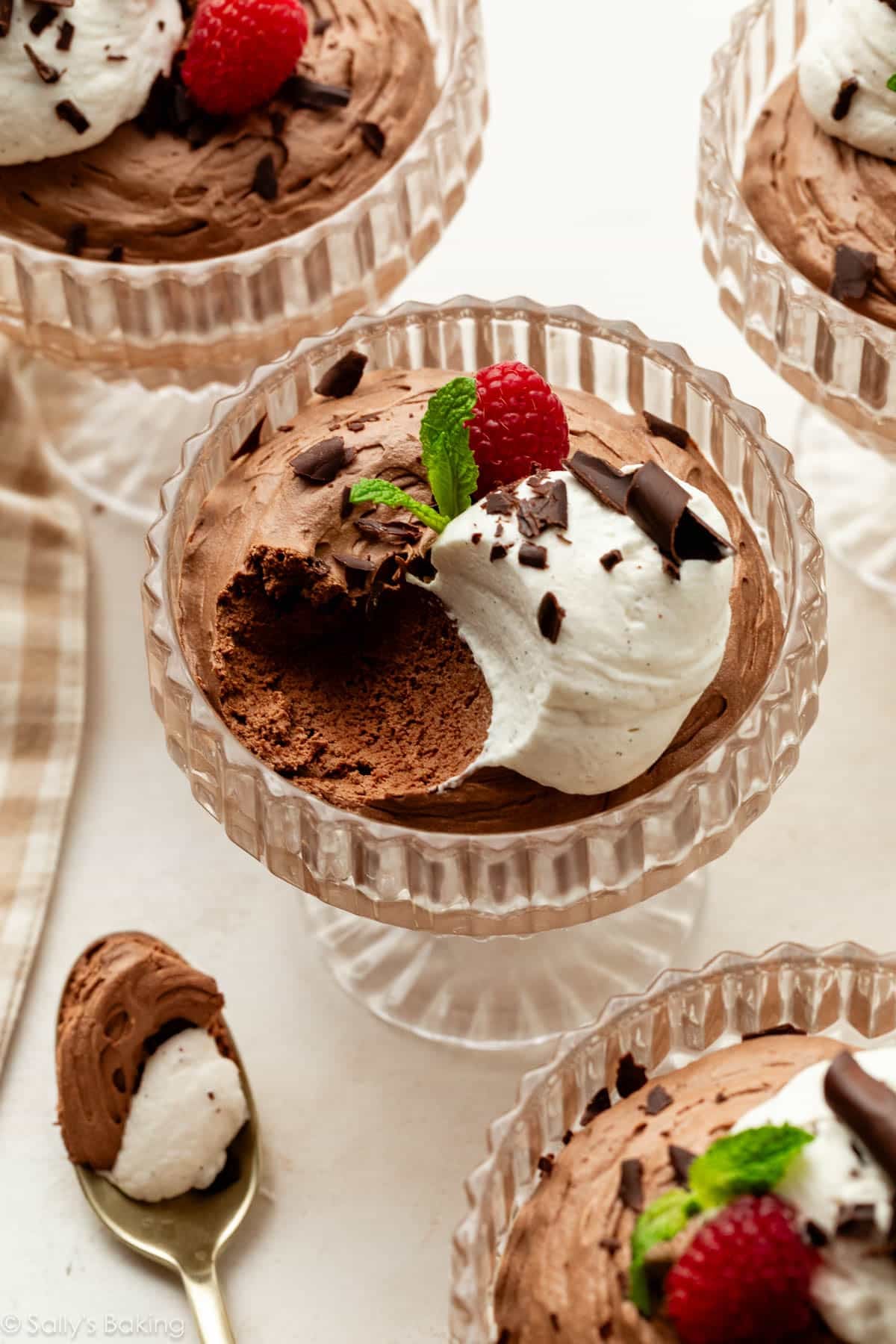 chocolate mousse in glass cups with whipped cream and raspberries.